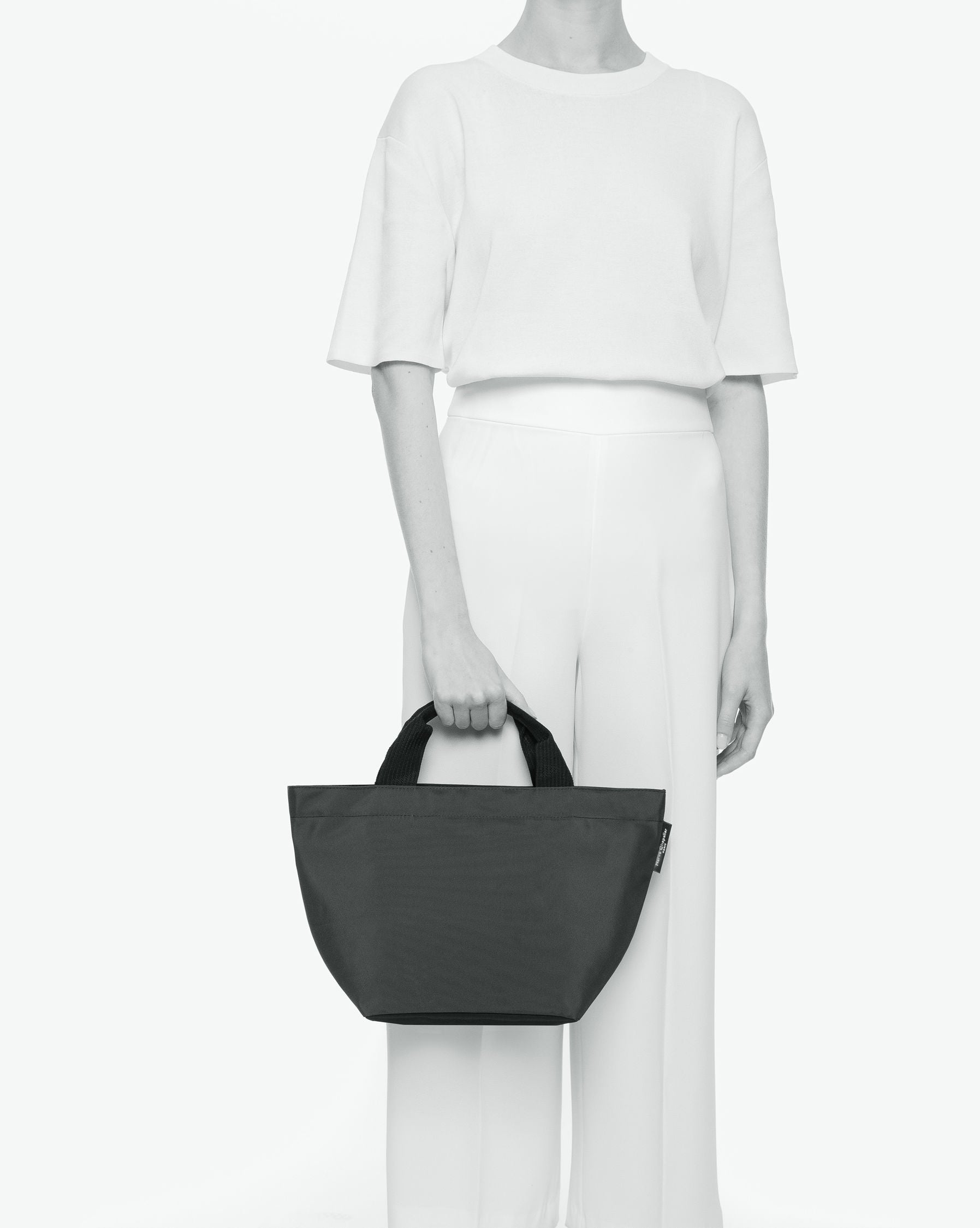 Sac à main cabas de couleur en nylon bicolore, à fond carré et dans un format M. Présence d'un double zip, de poignées courtes noires en polypropylène, et d'une étiquette de marque verte.