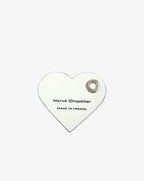 Packshot of a 122L flat charm in the shape of a heart with the Hervé Chapelier logo. The charm is made of leather with a eyelet in the middle in a XXS size. Charme en forme de coeur en cuir dans une taille XXS