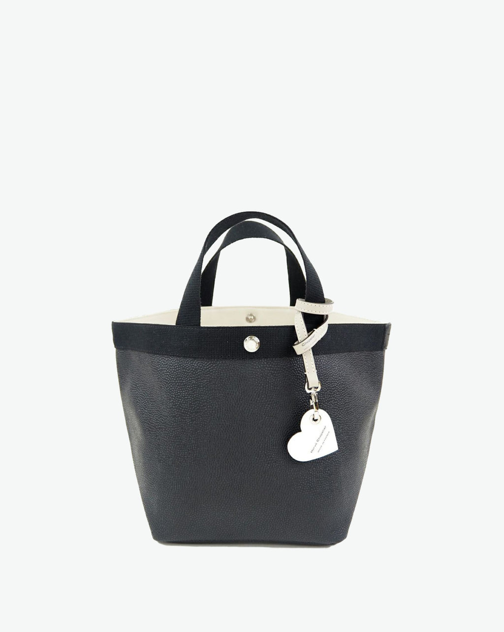 Packshot of a 122L flat charm in the shape of a heart with the Hervé Chapelier logo. The charm is made of leather with a eyelet in the middle in a XXS size. Charme en forme de coeur en cuir dans une taille XXS