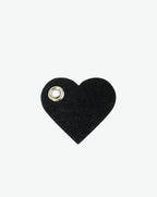 Packshot of a 122L flat charm in the shape of a heart with the Hervé Chapelier logo. The charm is made of leather with a eyelet in the middle in a XXS size. Charme en forme de coeur en cuir dans une taille XXS
