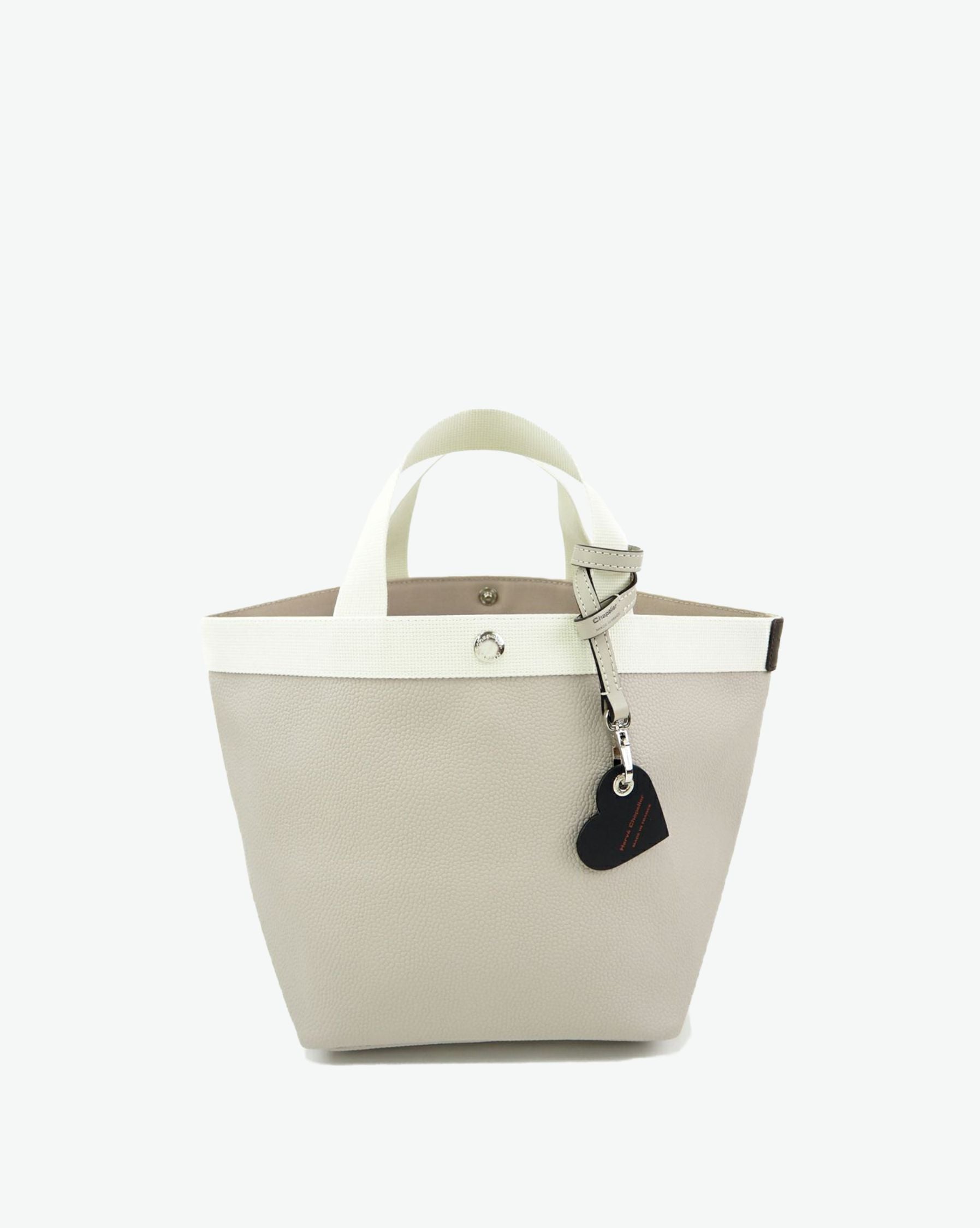 Packshot of a 122L flat charm in the shape of a heart with the Hervé Chapelier logo. The charm is made of leather with a eyelet in the middle in a XXS size. Charme en forme de coeur en cuir dans une taille XXS