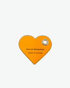 Packshot of a 122L flat charm in the shape of a heart with the Hervé Chapelier logo. The charm is made of leather with a eyelet in the middle in a XXS size. Charme en forme de coeur en cuir dans une taille XXS