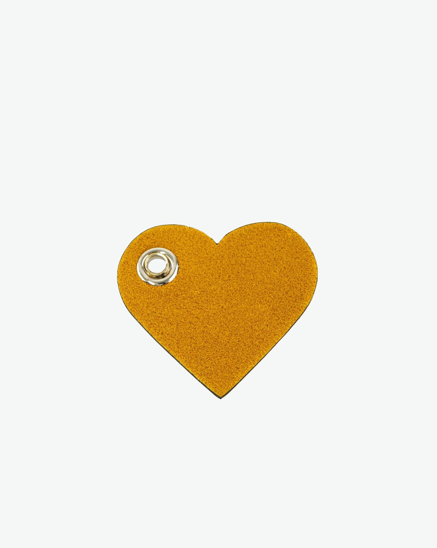 Packshot of a 122L flat charm in the shape of a heart with the Hervé Chapelier logo. The charm is made of leather with a eyelet in the middle in a XXS size. Charme en forme de coeur en cuir dans une taille XXS