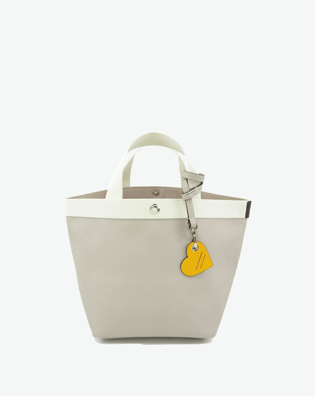 Packshot of a 122L flat charm in the shape of a heart with the Hervé Chapelier logo. The charm is made of leather with a eyelet in the middle in a XXS size. Charme en forme de coeur en cuir dans une taille XXS
