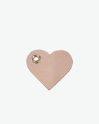 Packshot of a 122L flat charm in the shape of a heart with the Hervé Chapelier logo. The charm is made of leather with a eyelet in the middle in a XXS size. Charme en forme de coeur en cuir dans une taille XXS