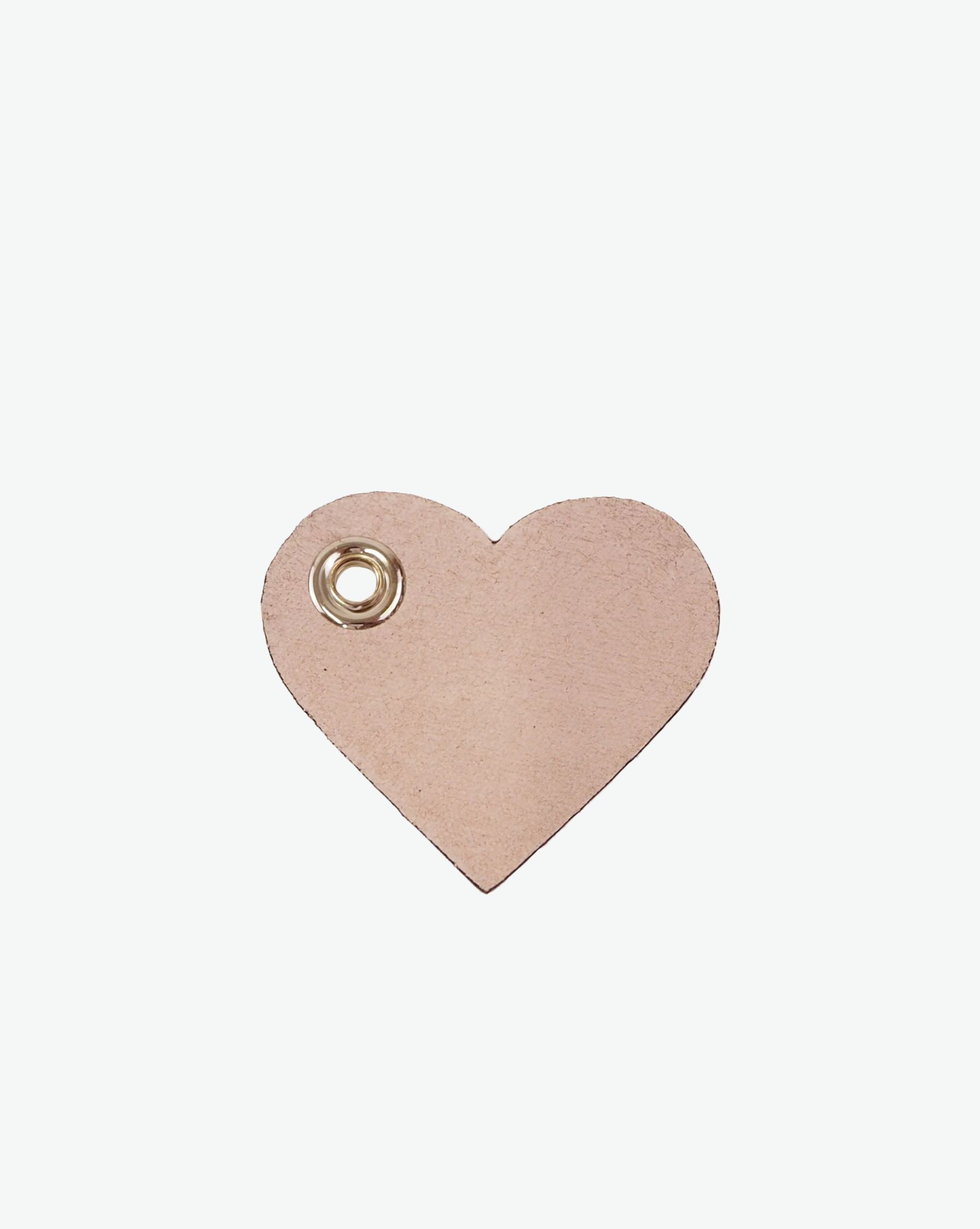 Packshot of a 122L flat charm in the shape of a heart with the Hervé Chapelier logo. The charm is made of leather with a eyelet in the middle in a XXS size. Charme en forme de coeur en cuir dans une taille XXS