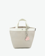 Packshot of a 122L flat charm in the shape of a heart with the Hervé Chapelier logo. The charm is made of leather with a eyelet in the middle in a XXS size. Charme en forme de coeur en cuir dans une taille XXS