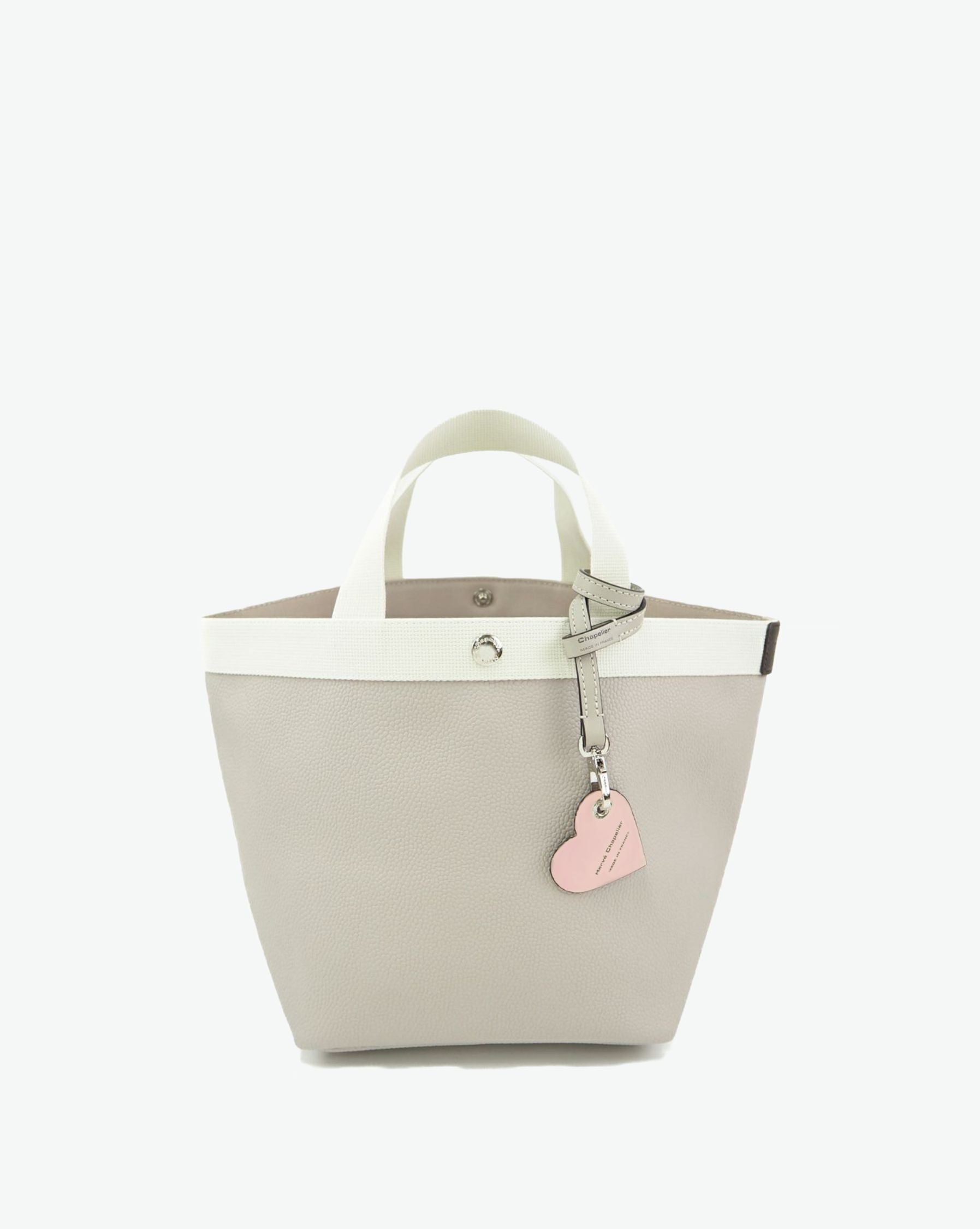 Packshot of a 122L flat charm in the shape of a heart with the Hervé Chapelier logo. The charm is made of leather with a eyelet in the middle in a XXS size. Charme en forme de coeur en cuir dans une taille XXS