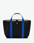 Sac à main en toile enduite grainée, à fond rectangulaire et dans une taille M, et aux poignées courtes de couleur à l'aspect coton faisant le tour du sac.