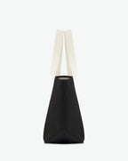 Sac porté épaule en toile enduite grainée, à fond rectangulaire et dans une taille M, et aux poignées longues de couleur à l'aspect coton faisant le tour du sac.