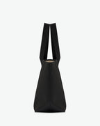 Sac porté épaule en toile enduite grainée, à fond rectangulaire et dans une taille M, et aux poignées longues de couleur à l'aspect coton faisant le tour du sac.