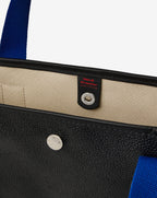 Sac porté épaule en toile enduite grainée, à fond rectangulaire et dans une taille M, et aux poignées longues de couleur à l'aspect coton faisant le tour du sac.