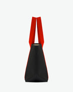 Sac porté épaule en toile enduite grainée, à fond rectangulaire et dans une taille M, et aux poignées longues de couleur à l'aspect coton faisant le tour du sac.