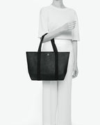 Sac porté épaule en toile enduite grainée, à fond rectangulaire et dans une taille M, et aux poignées longues de couleur à l'aspect coton faisant le tour du sac.