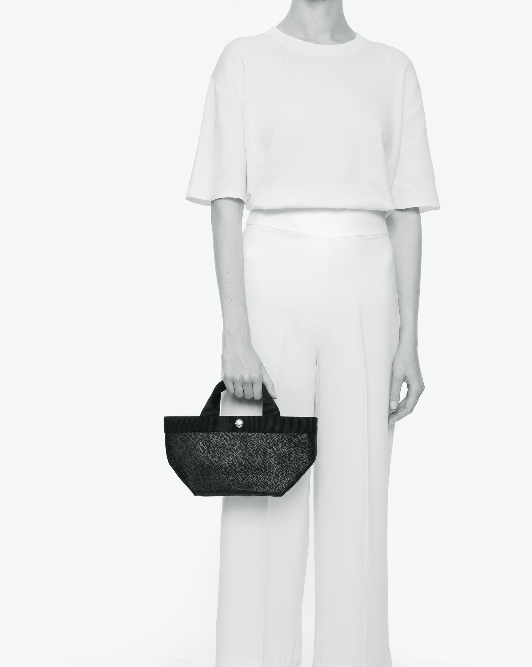 Sac à main en toile enduite grainée en taille S, au fond carré et aux poignées courtes de couleur à l'aspect coton, ainsi qu'à la poche intérieure avec bouton pression.