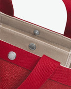 Sac à main en toile enduite grainée en taille M, au fond carré et aux poignées courtes de couleur à l'aspect coton, ainsi qu'à la poche intérieure avec bouton pression.