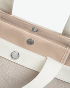 Sac à main en toile enduite grainée en taille L, au fond carré et aux poignées longues de couleur à l'aspect coton, ainsi qu'à la poche intérieure avec bouton pression.