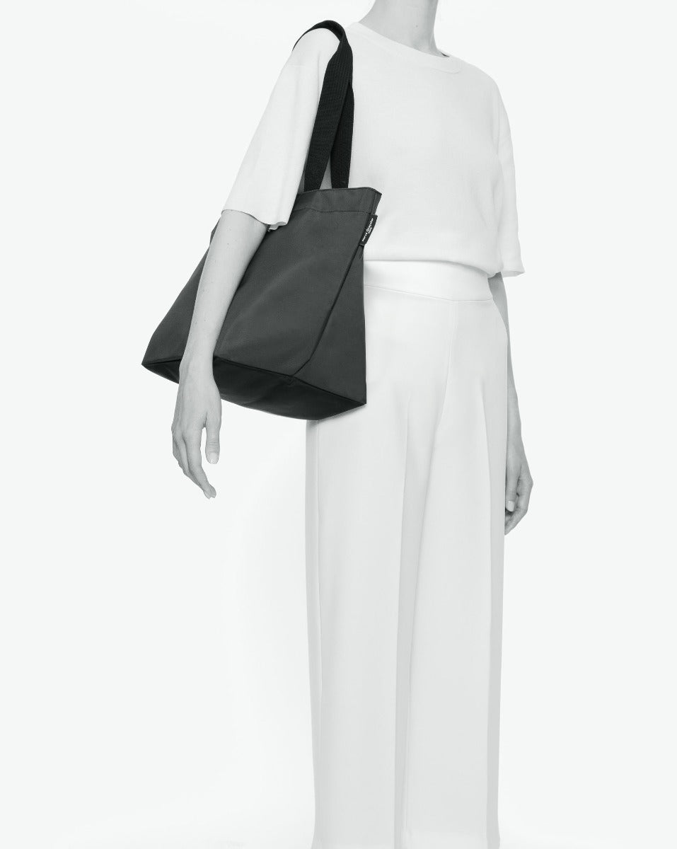 Sac cabas porté épaule de couleur en nylon bicolore, à fond carré et dans un format L. Présence d'un double zip, d'anses longues noires en polypropylène, et d'une étiquette de marque verte.