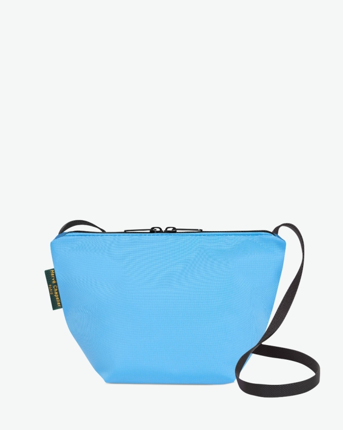 Visual on a white background of a shoulder bag standing upright and straight, with a long handle and a zip with double closure. The bag is made from nylon fabric in a blue color. The Hervé Chapelier label is affixed to the left-hand side.